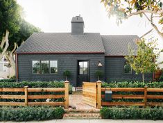 a gray house with wooden fence and bushes