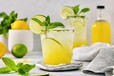 two glasses filled with lemonade, lime and mint