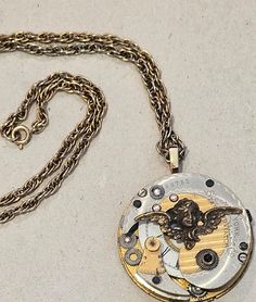 This gorgeous, handcrafted Steampunk Necklace is created from vintage pocket watch pieces from the turn of the 20th century. 100+ diameter.  The pendant is approximately 1/4" at its thickest part. The pendant is attached to a vintage brass color chain that is 18" on each side and closes with a lobster clasp. Comes in organza drawstring bag ready for gifting or storing the necklace. Study the pictures as they are the main part of this description. Thanks for looking. Pocket Watch Necklace, Antique Watch, Vintage Pocket Watch, Steampunk Necklace, Antique Watches, Guardian Angel, Watch Movement, Watch Necklace, Brass Color