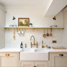 a kitchen with white cabinets and gold faucets