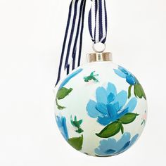 a blue flowered ornament hanging from a string on a white background,