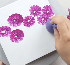 someone is using a sharp knife to cut paper with pink flowers on the white background