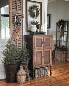 some plants are sitting on the floor in front of an old cabinet and window with shutters