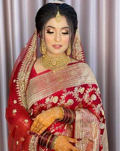 a woman in a red and gold bridal outfit with her hands on her chest