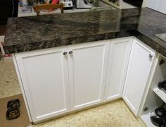 a kitchen counter top with white cabinets and black appliances in the backgroung