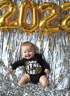 a baby is sitting in front of some foil balloons with the number 2052 on it