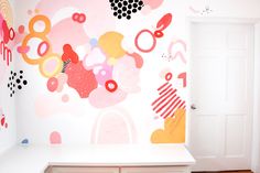 a room with a white door and colorful wallpaper