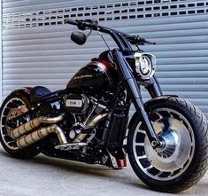 a black motorcycle parked in front of a garage door next to a metal roller door