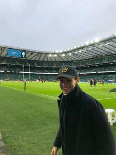 a man standing on top of a lush green field next to a soccer field in a stadium