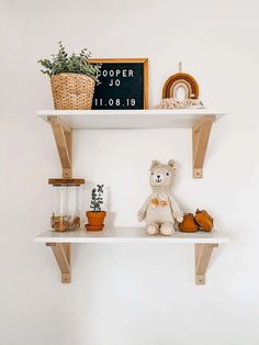 a teddy bear sitting on top of a white shelf