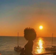 a woman sitting on a bench watching the sun set