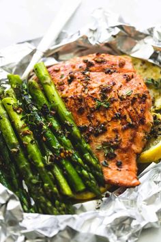 grilled salmon and asparagus in foil with lemon wedges on the side