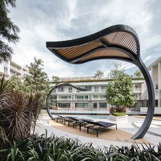 an artistic sculpture in the middle of a courtyard with tables and benches on it's sides