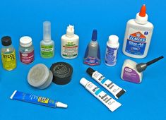 several different types of paint and glues on a blue surface with one being used as an adhesivement