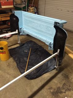 the back end of a blue bench is being worked on in a garage with tarp covering it