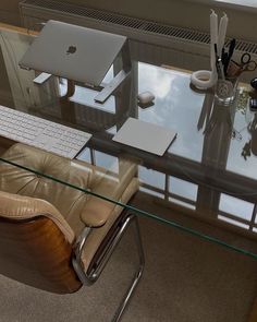 an office desk with a computer and chair in front of the glass top table is seen from above