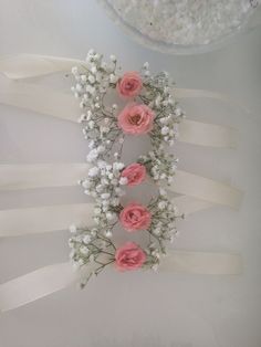 pink roses and baby's breath are arranged on ribbons