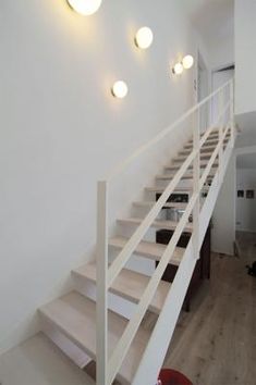 there is a white stair case in the room with three lights on each side and another light above it