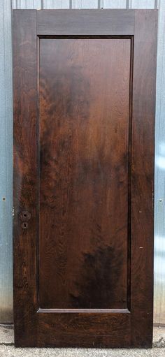 a wooden door sitting on top of a cement floor next to a metal building wall