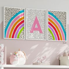 two canvases with the letter a and rainbow on them are hung above a shelf