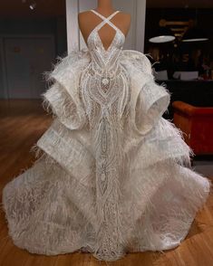 a dress made out of white feathers on display in a room with wooden floors and walls