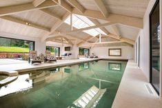 an indoor swimming pool in a house with large windows and wood beams on the ceiling