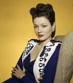 a woman sitting in a chair with her arms crossed and wearing a sash around her neck