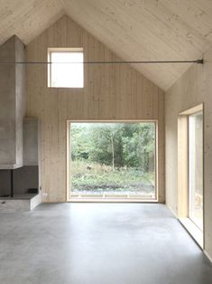 an empty room with large windows and wooden walls on both sides, in front of a fireplace