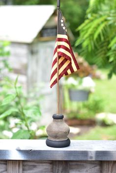 an american flag is on top of a small stone stand in front of a house