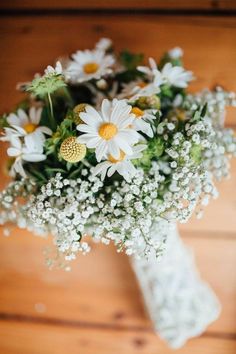 a bouquet of daisies and baby's breath on a table