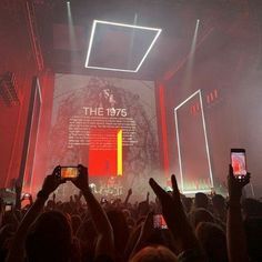 people taking pictures with their cell phones in front of a large screen at a concert