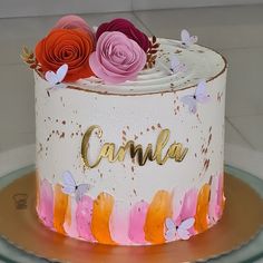 a white cake with pink, orange and yellow flowers on it that says camla