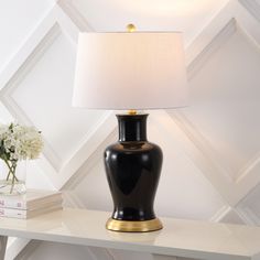 a table with a lamp on it next to a stack of books and a vase