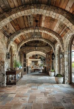 an arched walkway with stone walls and potted plants on either side, leading to the living room