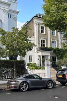 two cars parked in front of a large white house