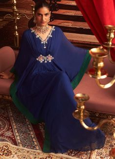 Make a statement at your next Sangeet or cocktail party in this stunning Electric Blue Chiffon Kaftan. With its exquisite embroidery along the neckline and sleeves, this Indo-Western draped kaftan offers the perfect blend of comfort and style for wedding guests. The flowing chiffon fabric drapes beautifully, creating a luxurious silhouette that's ideal for festive occasions. Whether it's a Sangeet or a cocktail event, this kaftan ensures you exude elegance. Composition : Kaftan - Chiffon & Lining - Satin Care: Dry Clean Only and Vacuum Storage This product can be customized for sleeves, blouse length and neckline Delivery : 2-4 weeks as the product is hand crafted. Check Size Guide or choose MySize for free customisation (All Sizes above XL can be made at 15% additional cost) For more info Draped Kaftan, Kaftan Set, Chiffon Kaftan, Style For Wedding, Vacuum Storage, Embroidered Chiffon, Sleeves Blouse, Cocktail Event, Draped Fabric