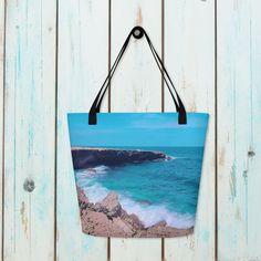 "**MAY NOT ARRIVE BEFORE CHRISTMAS** Take a piece of the beach with you wherever you go with our beach tote bag! The tote is printed with my unique design featuring the Caribbean Sea at Arikok National Park in in Aruba, the design is created from my original photography and edited to give it an artistic appearance. The bag is made from 100% polyester and includes an inside pocket. Plus, our design is printed using high-quality inks, ensuring that it won't fade over time. Whether you're headed to the beach, pool, or simply running errands, our tote bag is a fun and functional accessory. This beach tote makes the perfect gift for any beach lover in your life, or a treat for yourself to show off your love for the beach.  * 100% polyester * 16\" x 20\" * Inside pocket * Cotton webbing handles Themed Gifts, Beach Lover, Original Photography, Us Beaches, Caribbean Sea, Sea Beach, Functional Accessories, Beach Lovers, Beach Tote Bags