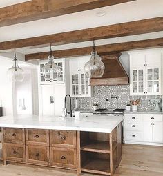 a large kitchen with white cabinets and wooden beams on the ceiling, along with marble counter tops