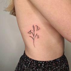 a woman's stomach with a small flower tattoo on her left side ribcage