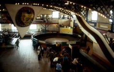 people are walking around in an old building with many stairs and large circular displays on the walls