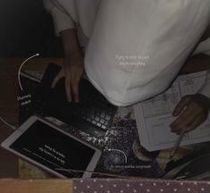 a person using a laptop computer on top of a table with papers and other items