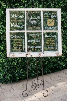 a sign that is sitting on top of a stand in front of some plants and bushes