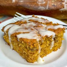 a piece of carrot cake on a white plate with a fork in front of it