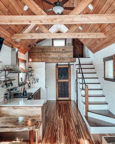 the inside of a tiny house with wood floors and stairs leading up to an open kitchen area