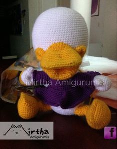 a crocheted stuffed bird wearing a purple shirt