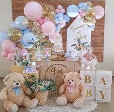 two teddy bears sitting next to each other in front of a cake table with balloons