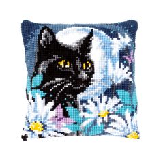 a black cat with yellow eyes sitting on top of a blue and white flowered pillow