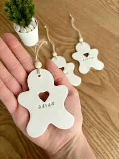 a hand holding two ornaments with the word love on them and a potted plant in the background