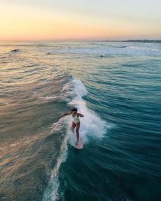 a person riding a surfboard on a wave in the ocean at sunset or dawn