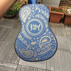 a blue and gold guitar case sitting on top of a wooden floor next to potted plants